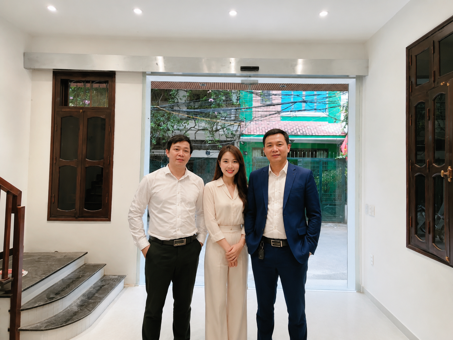 Ba nhân viên văn phòng mặc sơ mi và vest đứng trong sảnh nhà mới sáng sủa